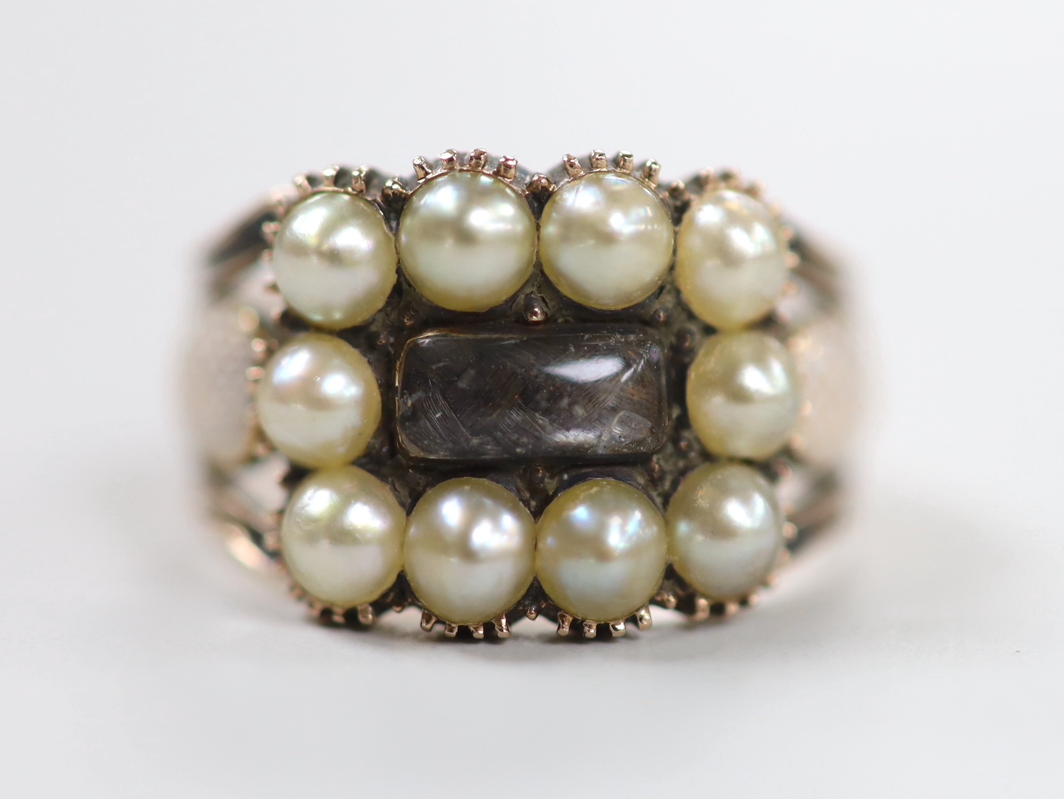 A 19th century yellow metal, plaited hair, enamel and split pearl set mourning ring, size P, gross weight 5.3 grams
